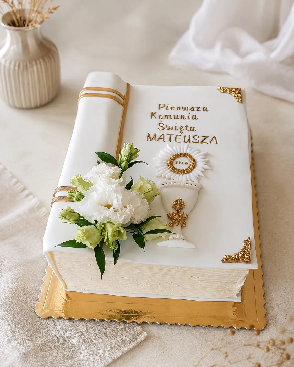 Tort w kształcie białej księgi ze złotymi okuciami, kielichem z hostią i napisem Pierwsza Komunia Święta Mateusza