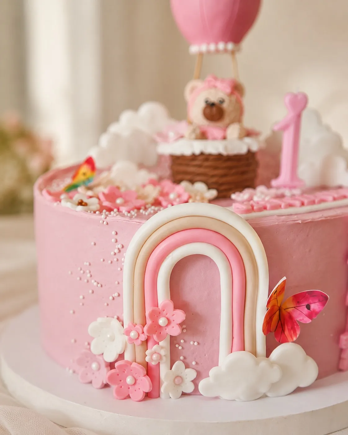 Zbliżenie na pastelową tęczę z kwiatuszkami u podstawy tortu i balon z misiem w tle