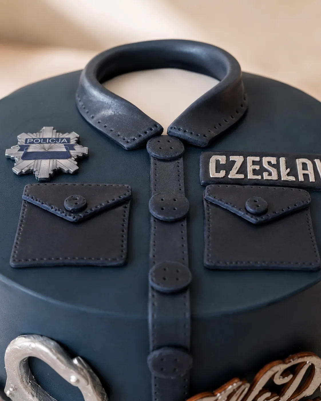 Zbliżenie na kołnierzyk, kieszonki i odznakę Policji na wierzchu tortu
