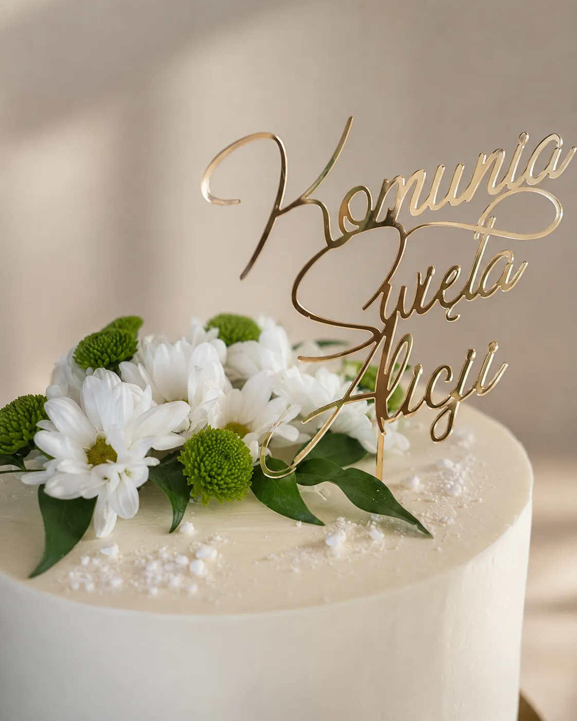 Zbliżenie na białe kwiaty i złoty toper z imieniem